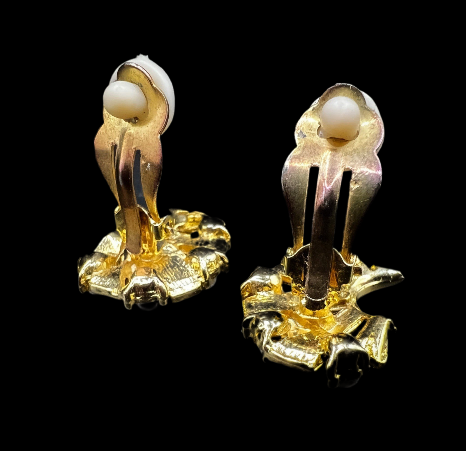 Rear view of both earrings, displaying the clip-on fastenings and polished gold-tone base with sculpted detail.